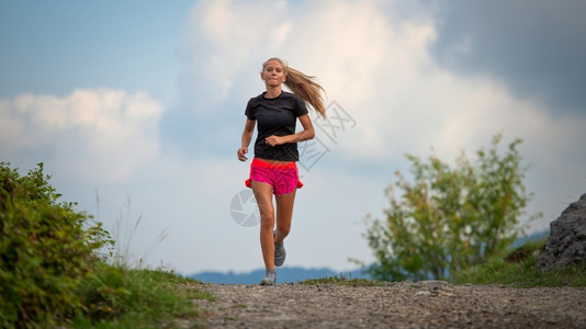 活动运员在山土上奔跑的身材瘦弱年轻女孩赛跑者图片