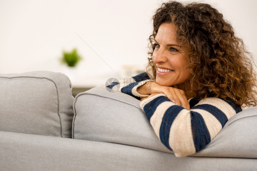 坐在沙发上家里美丽的幸福女人图片