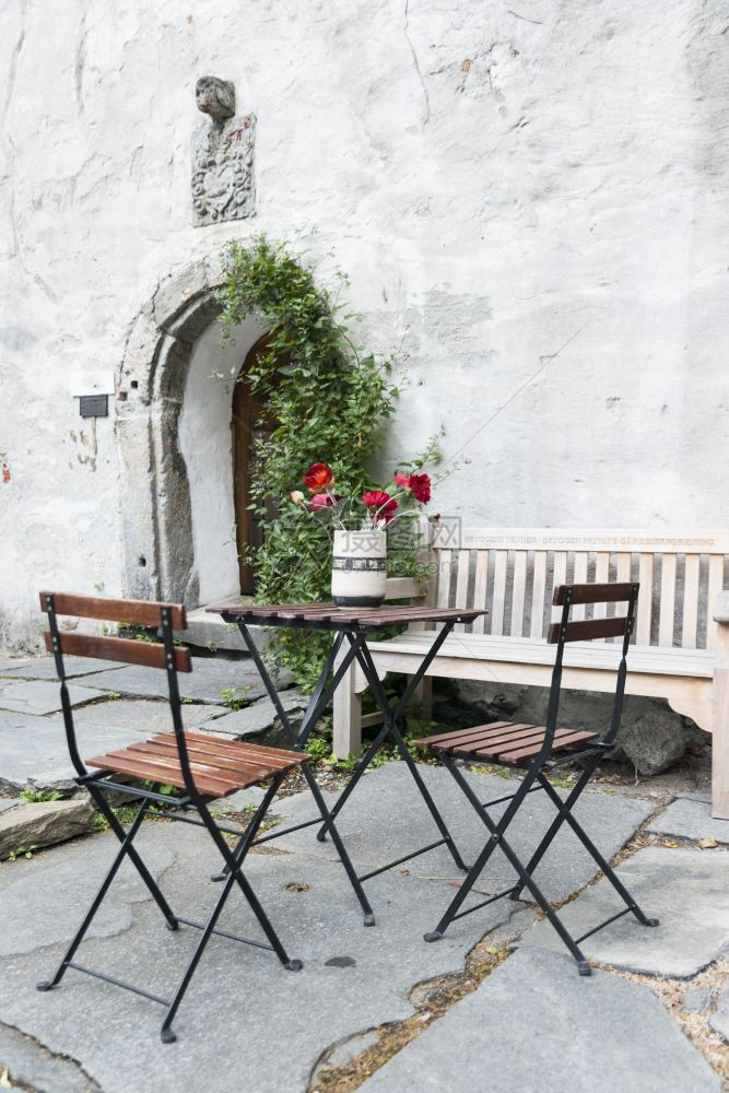 挪威卑尔根的旧露台有红花旧墙前桌椅带弓形入口开幕布吕根阳台图片