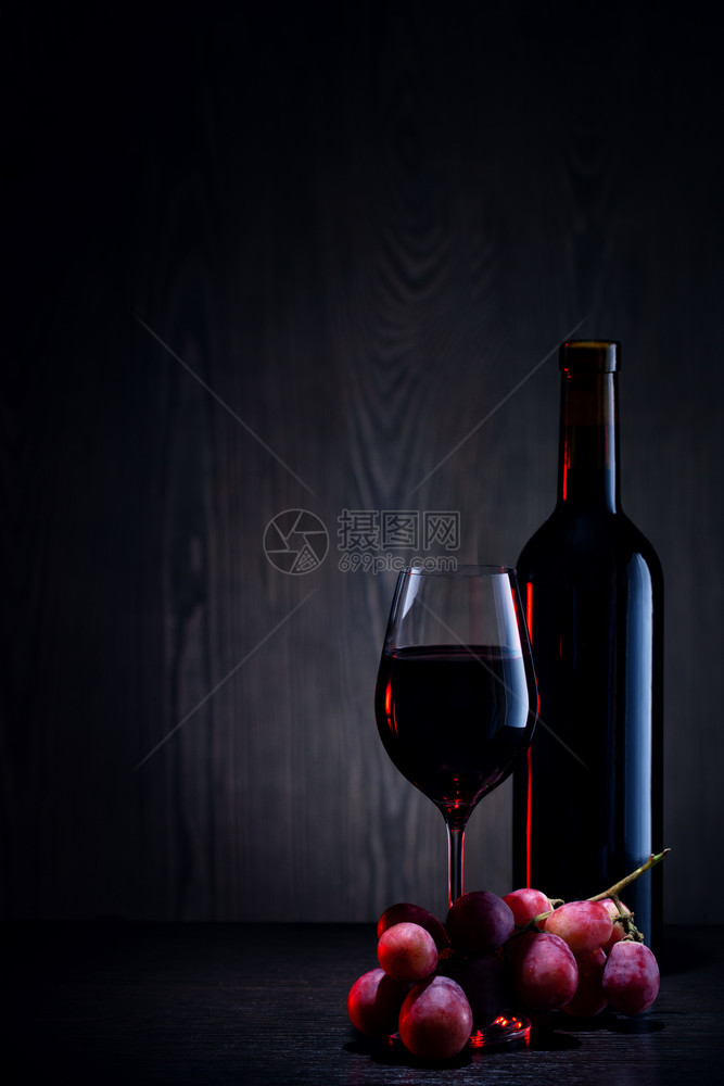 喝玻璃杯中的红酒瓶子和木桌上的一串葡萄玻璃瓶中的红酒和木桌上一串葡萄水果庆典图片