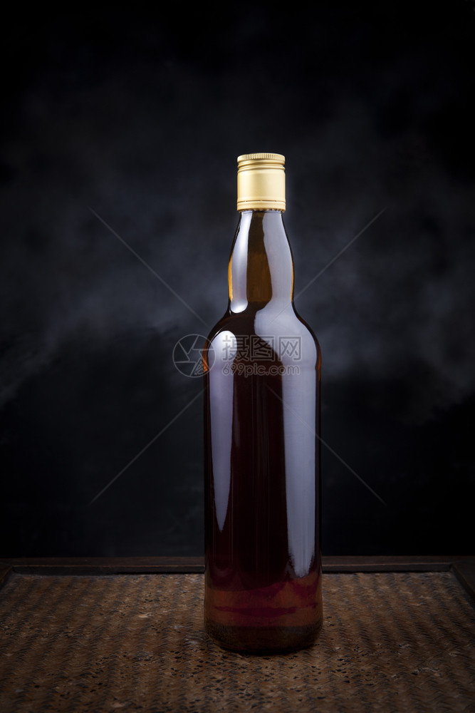 液体棕色的包装用于木材背景的多用途威士忌瓶的木本底威士忌瓶子的图片
