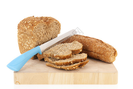 厨房蓝色的棕多谷物面包切割板上有刀子在白色背景上被孤立木板图片