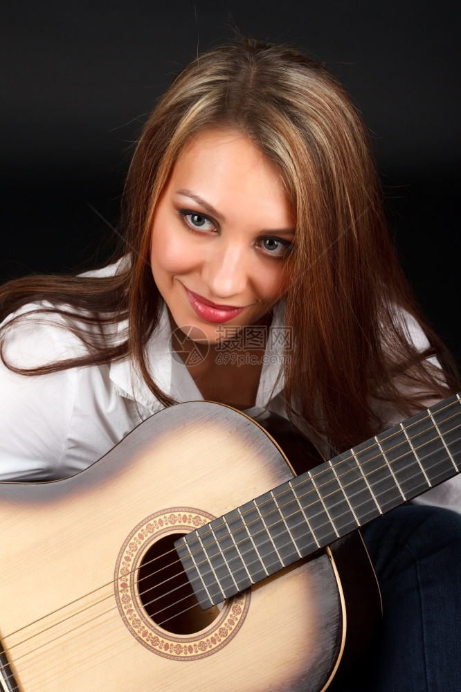 一个年轻有魅力的女人肖像带着黑色背景的吉他化妆品眼睛一种图片