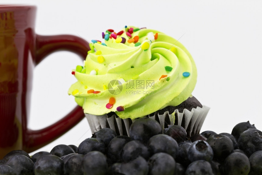 深度巧克力蛋糕紧贴上绿色霜冻突出焦点红色杯子放在背景蓝莓浅的焦度深处蓝莓放在前景重点红色的图片