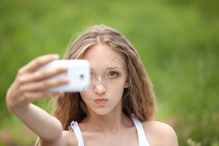 美丽的女青少年用电话面对自以为是的少女听到年轻肖像图片