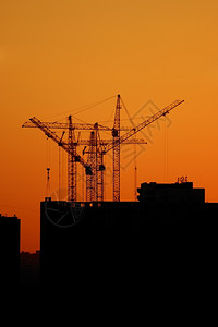 行业住房高的日落时建造起重机组月光对橙色天空背景