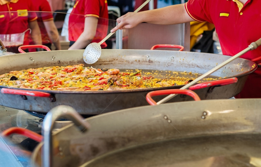 白饭盘子在街头食品市场一个配有海鲜和鸡肉的西班牙传统辣椒饼配有海鲜和鸡手图片