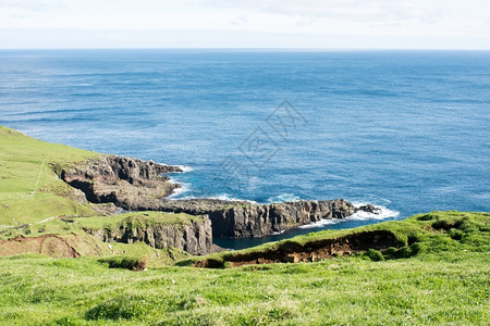 草地海洋多岩石的法罗群岛地貌景观法罗群岛地貌景观悬崖蓝海和绿草图片