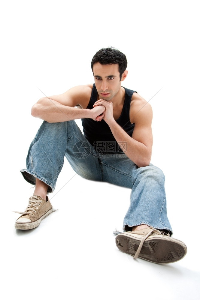 可爱的友好穿着黑顶和牛仔裤的白人帅哥坐在地上思考与世隔绝感的图片