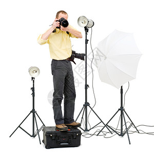 留学我们更专业一名专业摄影师站在一个飞行箱子上在一个工作室里得到更高的角度周围有3个摄像头灯光单反拍照片背景