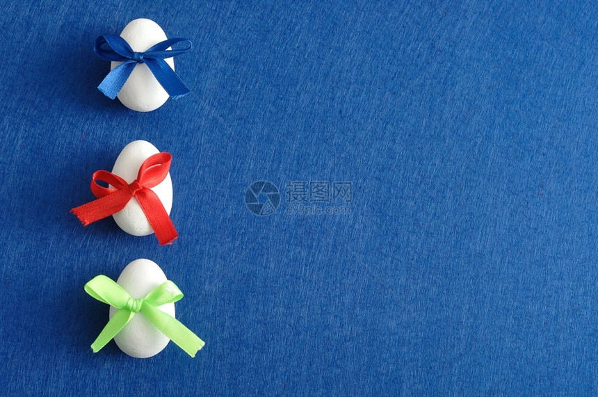 传统的三个白色东边鸡蛋装饰着色彩多的弓美丽季节图片