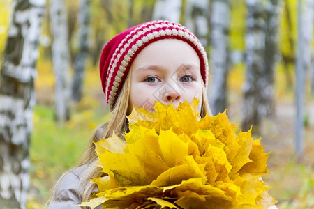 秋天拿着金黄色树叶的小女孩图片