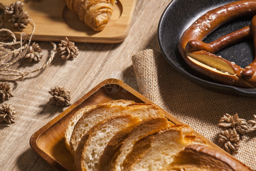 新鲜的法语面包括牛角法国和脆饼放在餐盘和排布板以及供客户使用的木制餐桌上羊角面包图片