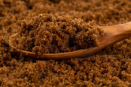 水晶湿糖蜜含背景的木勺中棕色混血糖图片