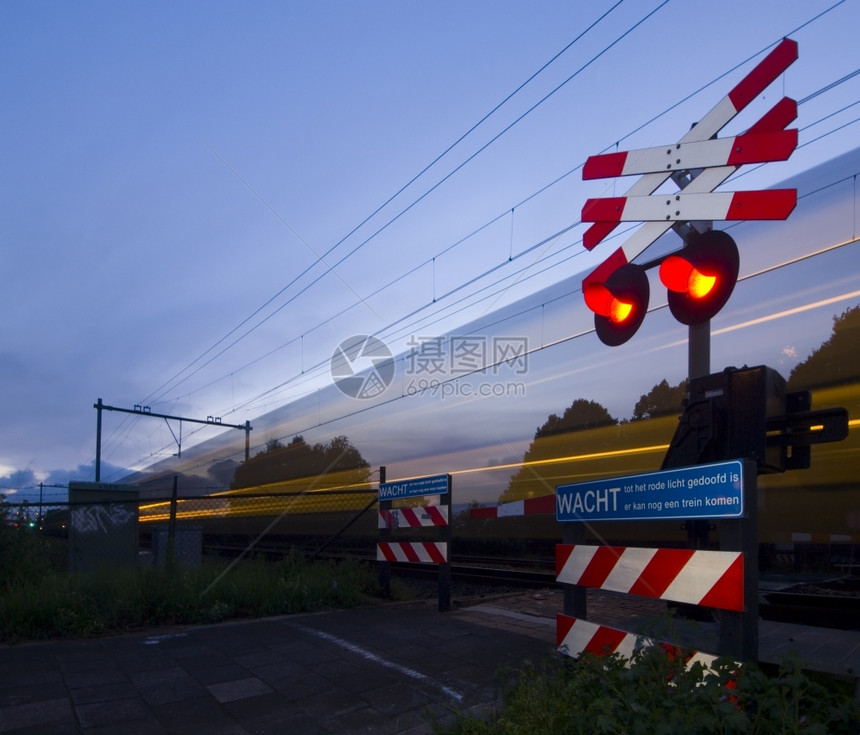 一种金属丝列火车在夏天晚上经过一个铁路境点四周围着栅栏和铁丝网等待图片