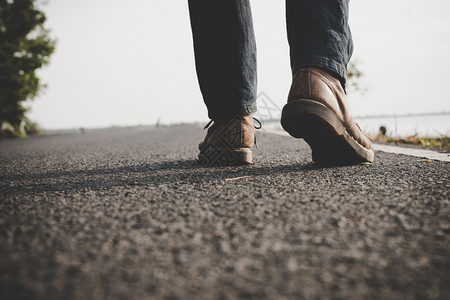 游客靠近在农村公路上行走的年轻旅游男子街道运动鞋图片