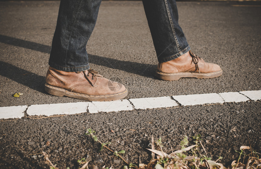 腿步靠近在农村公路上行走的年轻旅游男子小路图片