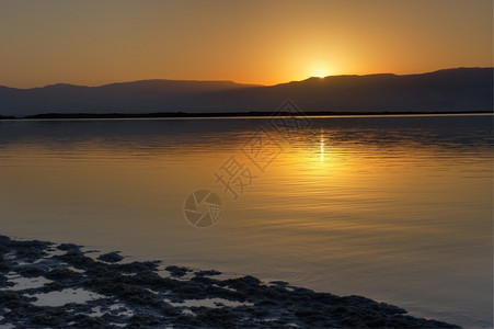 早晨黎明时的死海和在约旦山上升起的第一道太阳光死的射线图片