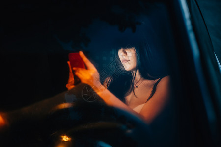 吸引人的独自女青年在车里使用她的智能手机运输图片