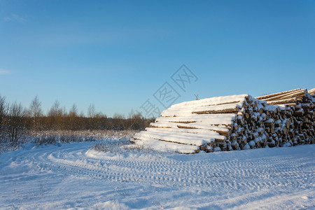 木材自然树大堆雪覆盖了路边的木头在明晴冬季白天背景图片