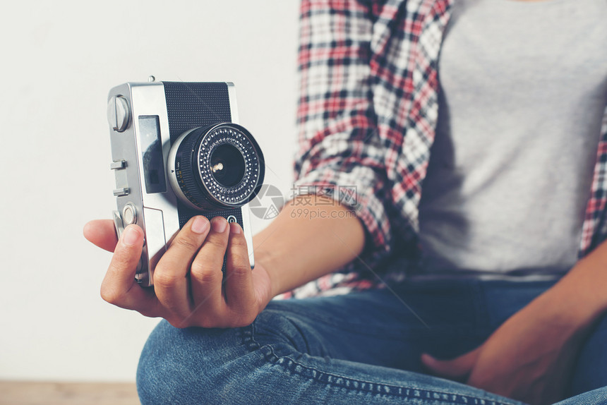 拍照年轻时装摄影师手握着反光相机坐在青年时装摄影师手持反光相机坐在木地板上掌声数字的复古图片