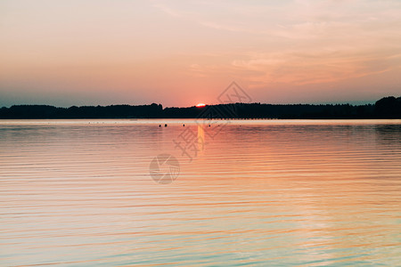 平静的日落隐藏太阳躲在地平线后面位于Chiemsee湖图片