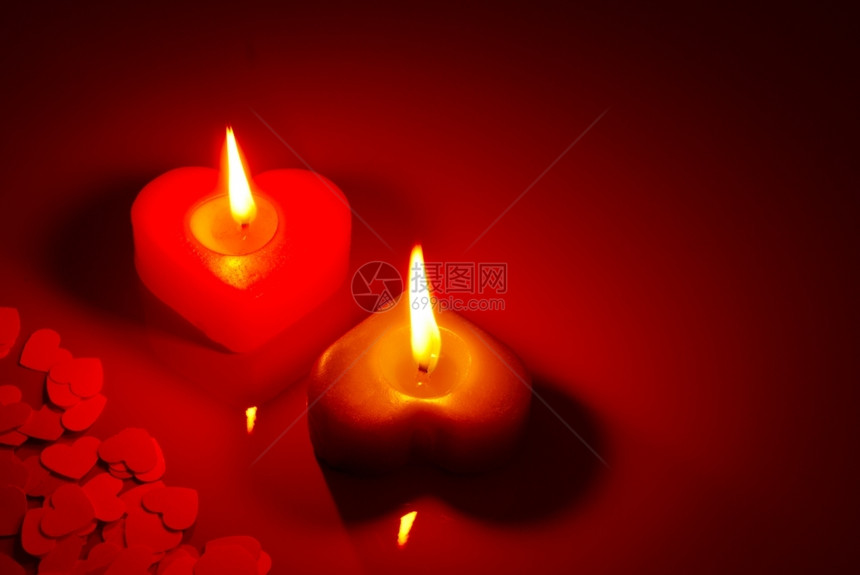 优雅圣诞节红桌上两个燃烧的心形蜡烛红色图片