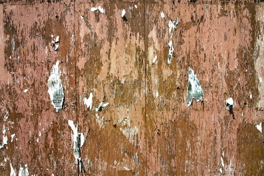 撕开脱皮一堵古老的风湿胶合板墙覆盖在剥皮涂料中还有被钉住后撕掉的旧传单残余外部的图片