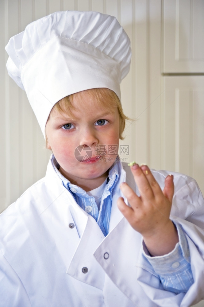 孩子品尝一个男穿着厨师的制服露出他脏手指粘上甜食成分她的科子一直在品味吸引男孩们的脸烹饪图片