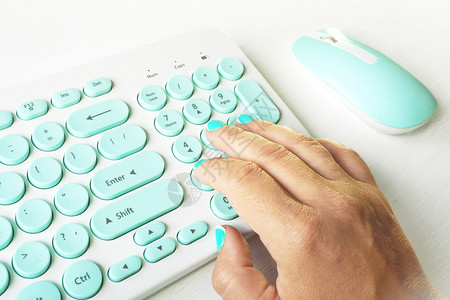 白色和蓝键盘上白桌子的有蓝色指甲型女手员工一种蓝色的图片
