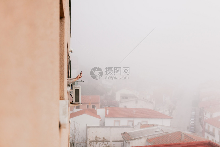 在隔离期间妇女用手机从窗户上伸出双臂外部的去坐月子图片