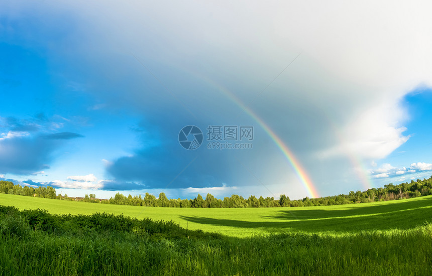 雨在一片大云底的绿地上笼罩着明亮多彩虹超过草地图片