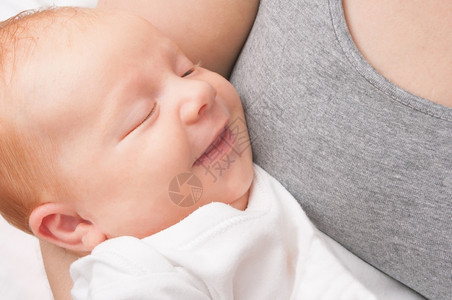 关闭母亲怀着微笑的新生婴儿白种人健康色的背景图片