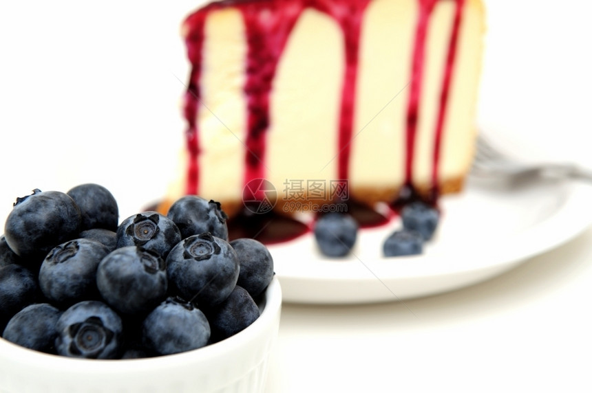 倒了一种乳酪蛋糕新鲜的蓝莓和芝士蛋糕白加上一份蓝莓酱汁倒在顶部上面盘子旁边有新鲜的浆果在蛋糕旁边加了薄荷叶图片