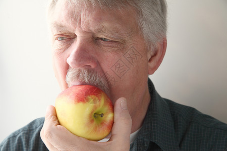 水果新鲜的年纪大男人咬着新鲜苹果一种背景图片