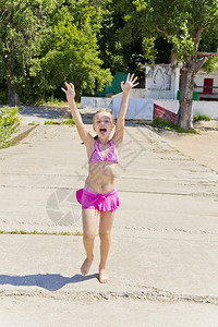 白泳衣跳跃小孩身穿粉红色泳衣在河岸边玩耍的小女孩背景