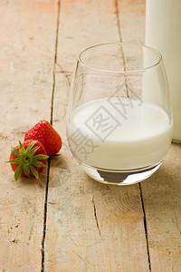 液体瓶子在木制桌上加草莓的牛奶杯照片乳制品图片