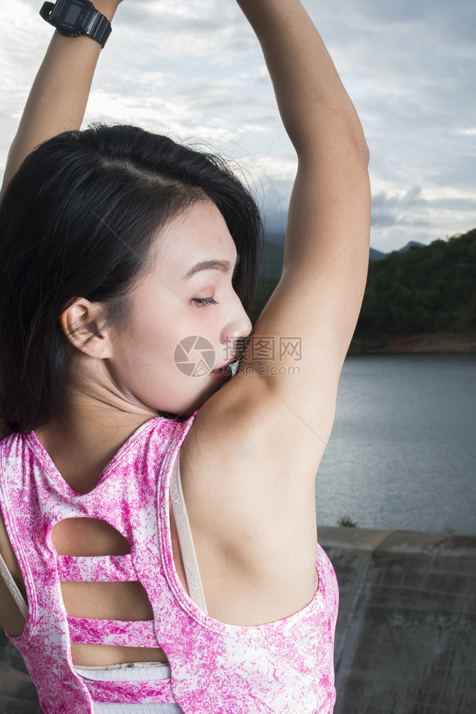 运动员身体健康的妇女做伸展运动她的双臂美丽图片