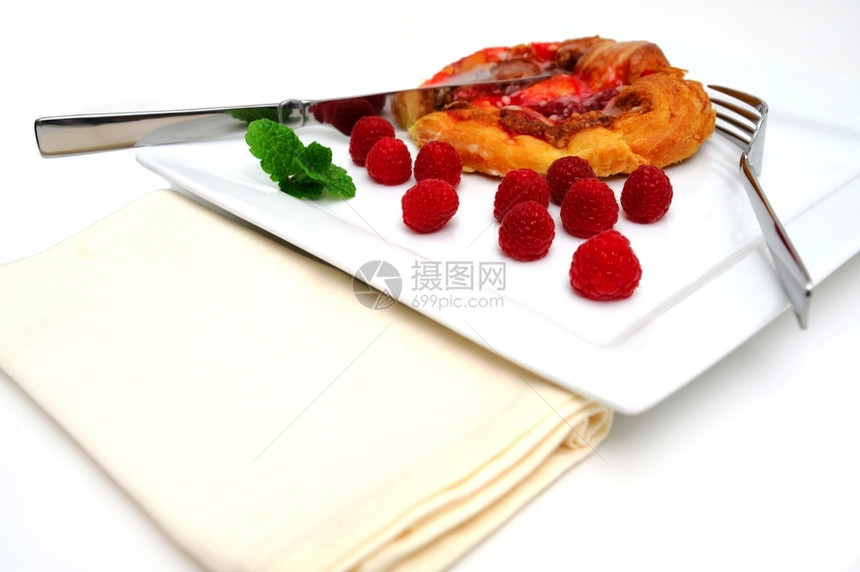 食物丹麦糕饼莓蛋草美饼配有新鲜的红莓和薄荷加料用叉子刀和餐巾纸在平方白板上供餐色的棕图片