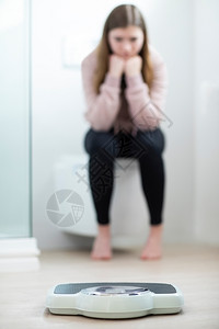 家坐在浴室看天花板的不快乐少女坐着称重孩图片