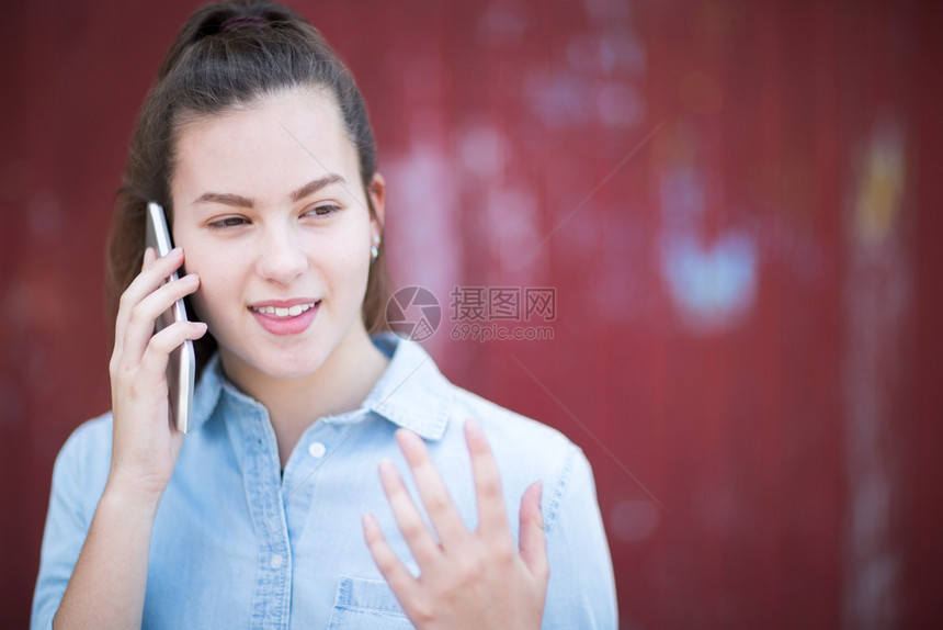 移动的连接城市环境中在移动电话上与外边交谈的少女人数孩图片