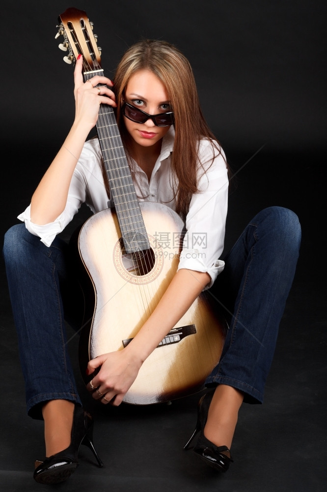看一个年轻有魅力的女人肖像带着黑色背景的吉他人类成图片