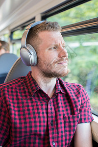 垂直的胡须通勤年轻人在上班途中听音乐时用耳机收听图片