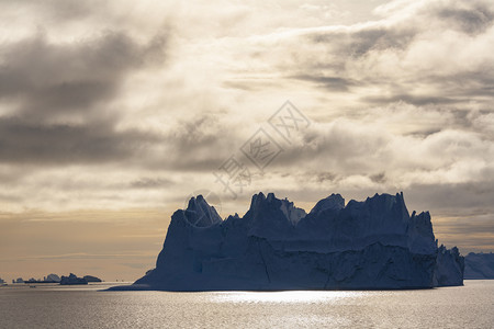 黄昏东格陵兰高士比森德的大型冰山在午后阳光下漂浮晚的极图片
