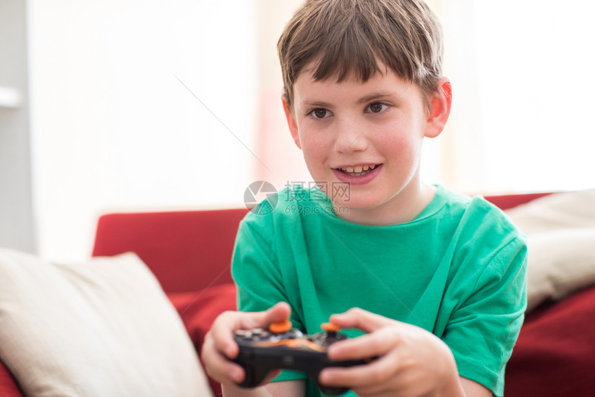 在家玩电脑游戏时坐在沙发上的男孩线游戏玩家人们图片