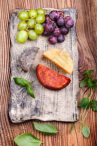 起司陶瓷制品木头奶酪和葡萄上面的旧木制板上手工作陶瓷板上的巴锡叶图片