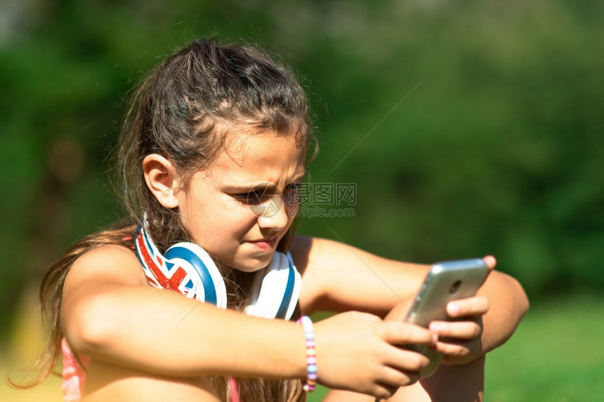 学校年轻的小女孩用她智能手机探索社交网路现代的图片