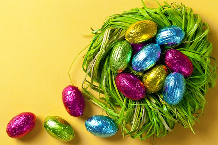 颜色彩复活节蛋在绿巢中黄纸背景上的假日组合物顶视图丰富多彩的蓝色图片