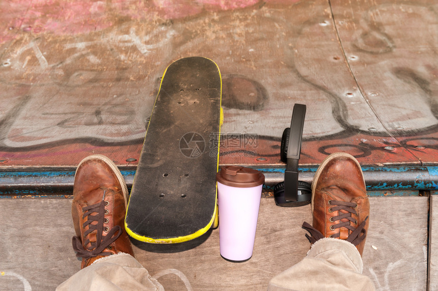 滑板手运动城市的用塑料咖啡杯在斜坡上滑冰和耳机图片