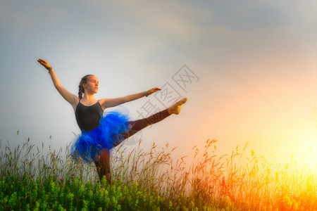 太阳自然青春美丽芭蕾舞者在日落时花朵的草原上户外跳舞通图片